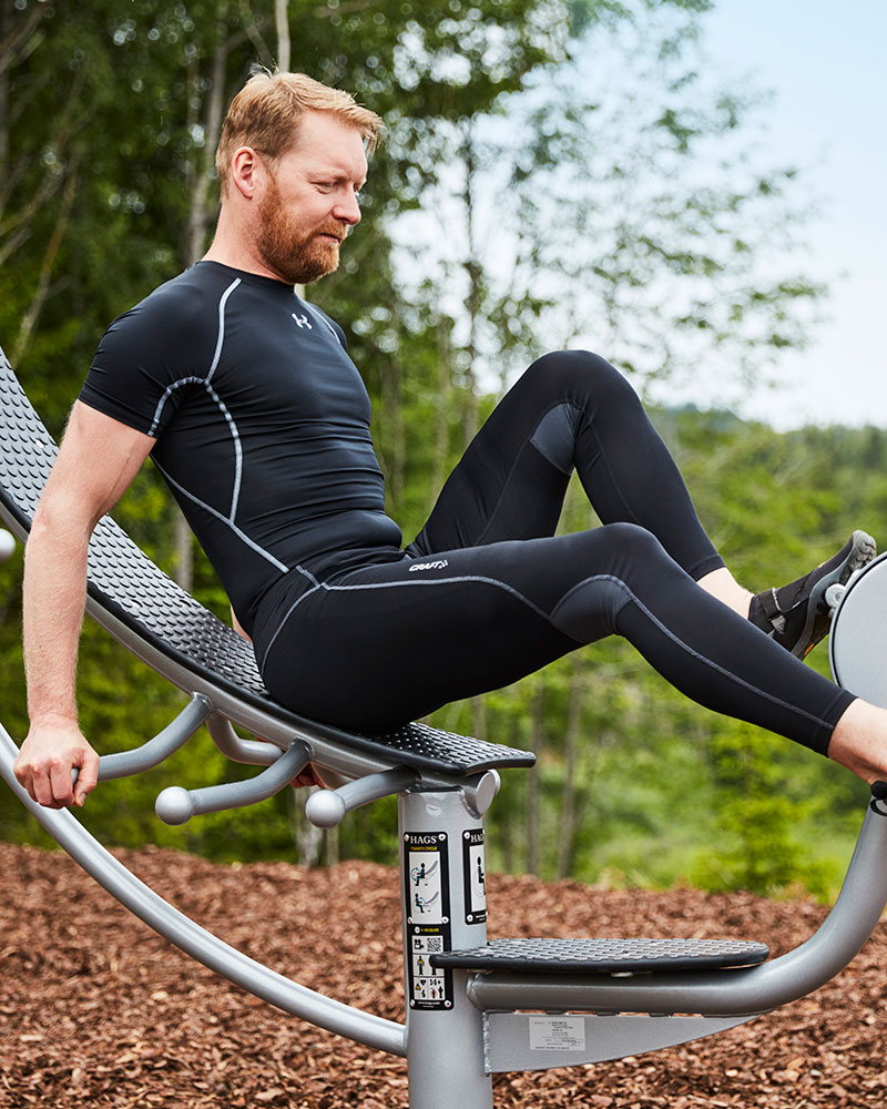 A man is exercising on a trinity cycle, which is a laid back bike for exercise.